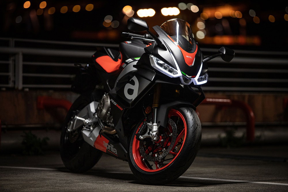 Aprilia RS660 parked up at night with the headlights on